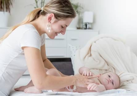 A mother changes her baby's diaper